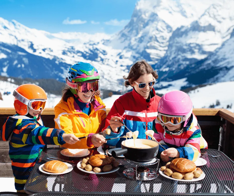 A family gathers around a table, enjoying a warm fondue meal after skiing in the Alps—one of the best alternatives to Disney World vacation for winter-loving families.